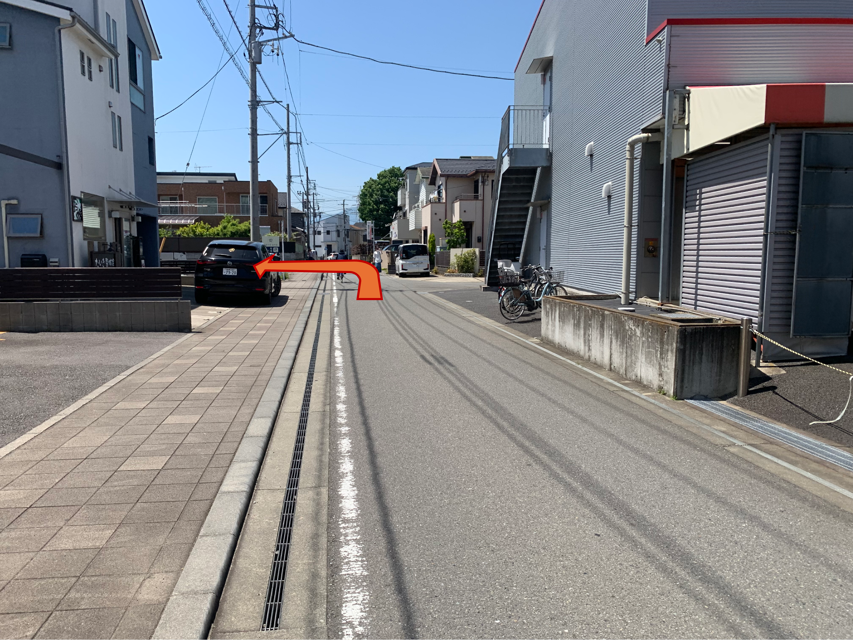 建物の奥左手に駐車場が見えています。この道路は一方通行となっています。